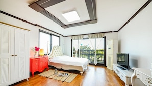 Un dormitorio con cama, cómoda, televisor y ventana con vistas a la vegetación.