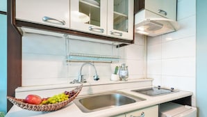 Una cocina con armarios blancos, un lavamanos doble y un frutero en la encimera.