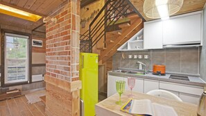 A modern kitchen with a brick accent wall, a yellow appliance, and a dining area with a book and glasses. - Gapyeong Beethoven House Pension (Gapyeong)