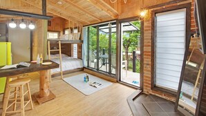 A compact room with a bunk bed, a small desk with a stool, and a large sliding glass door leading to an outdoor patio. - Gapyeong Beethoven House Pension (Gapyeong)