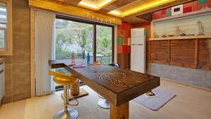 A modern kitchen with a wooden bar, a refrigerator, and a view of the outdoors. - Gapyeong Beethoven House Pension (Gapyeong)