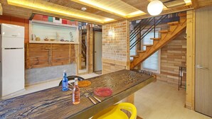 A modern kitchen with a wooden table, a built-in stove, and a brick wall. - Gapyeong Beethoven House Pension (Gapyeong)