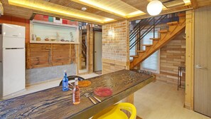 A modern kitchen with a wooden table, a built-in stove, and a brick wall. - Gapyeong Beethoven House Pension (Gapyeong)