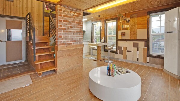 Una cucina moderna con parete decorata in mattoni, una scala in legno e un tavolo rotondo bianco con bottiglie.