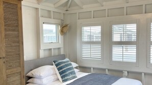 Une chambre à coucher avec un lit, une armoire en bois et une fenêtre avec des volets.