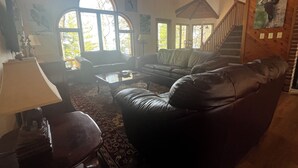A living room with leather sofas, a coffee table, and a staircase.
