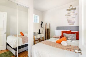 A bedroom with two beds, a desk, and a ladder.