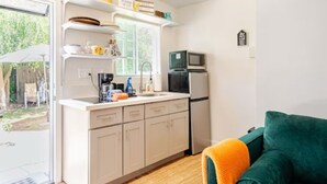 Una cucina compatta con mobili bianchi, un forno a microonde e una finestra.
