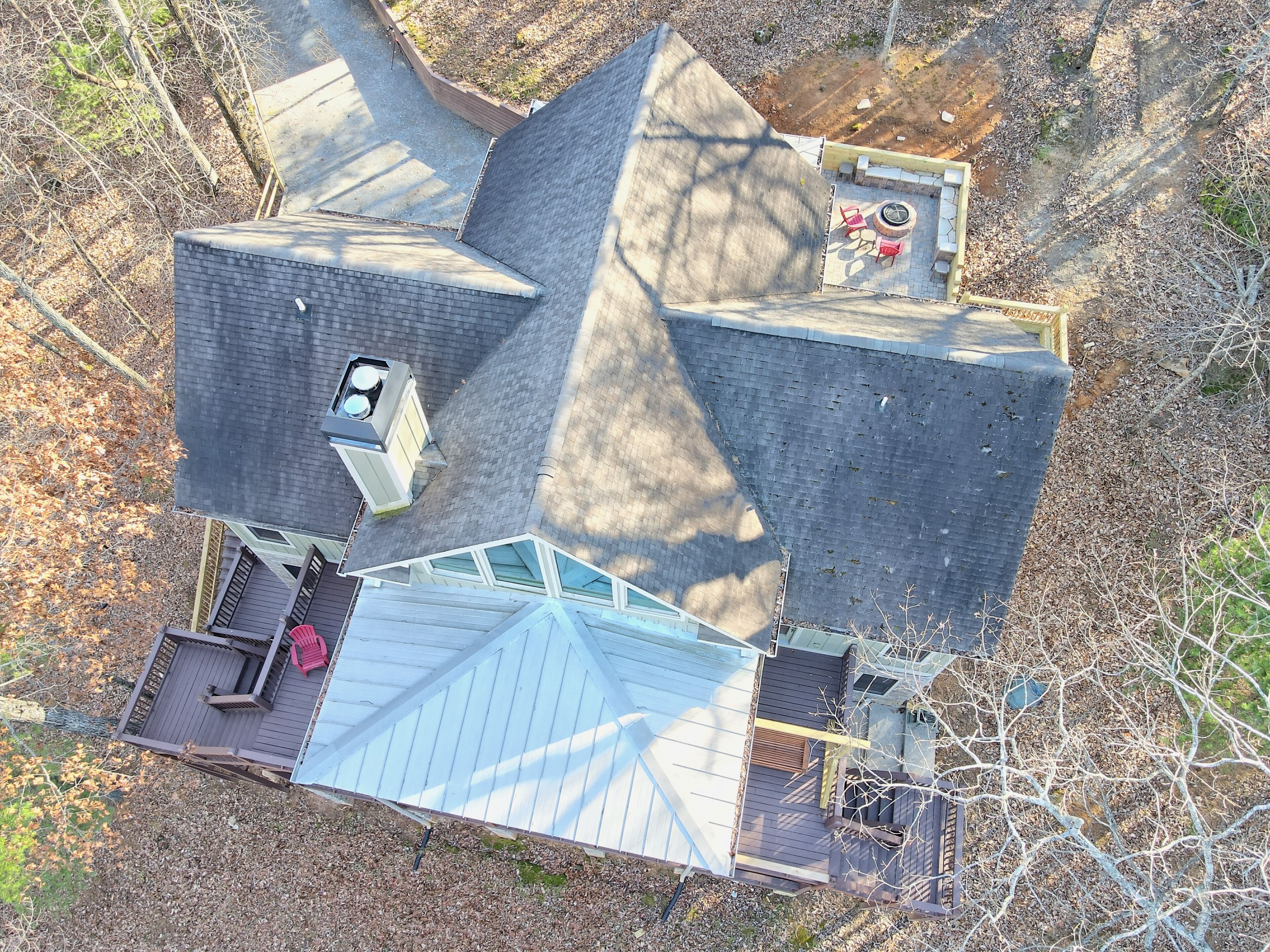 Una casa con techo inclinado, una terraza con fogón y un pequeño espacio de estar al aire libre.