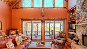 A cozy living room with a leather couch, a floral armchair, and a fireplace. - Ultra Peaceful Retreat! Large Cabin, 2 Masters on Main, Games & Lake! (Ellijay)