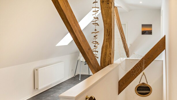 Eine Treppe mit Holzbalken, einem weißen Heizkörper und einem gerahmten Bild an der Wand.