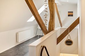 Eine Treppe mit Holzbalken, einem weißen Heizkörper und einem gerahmten Bild an der Wand.