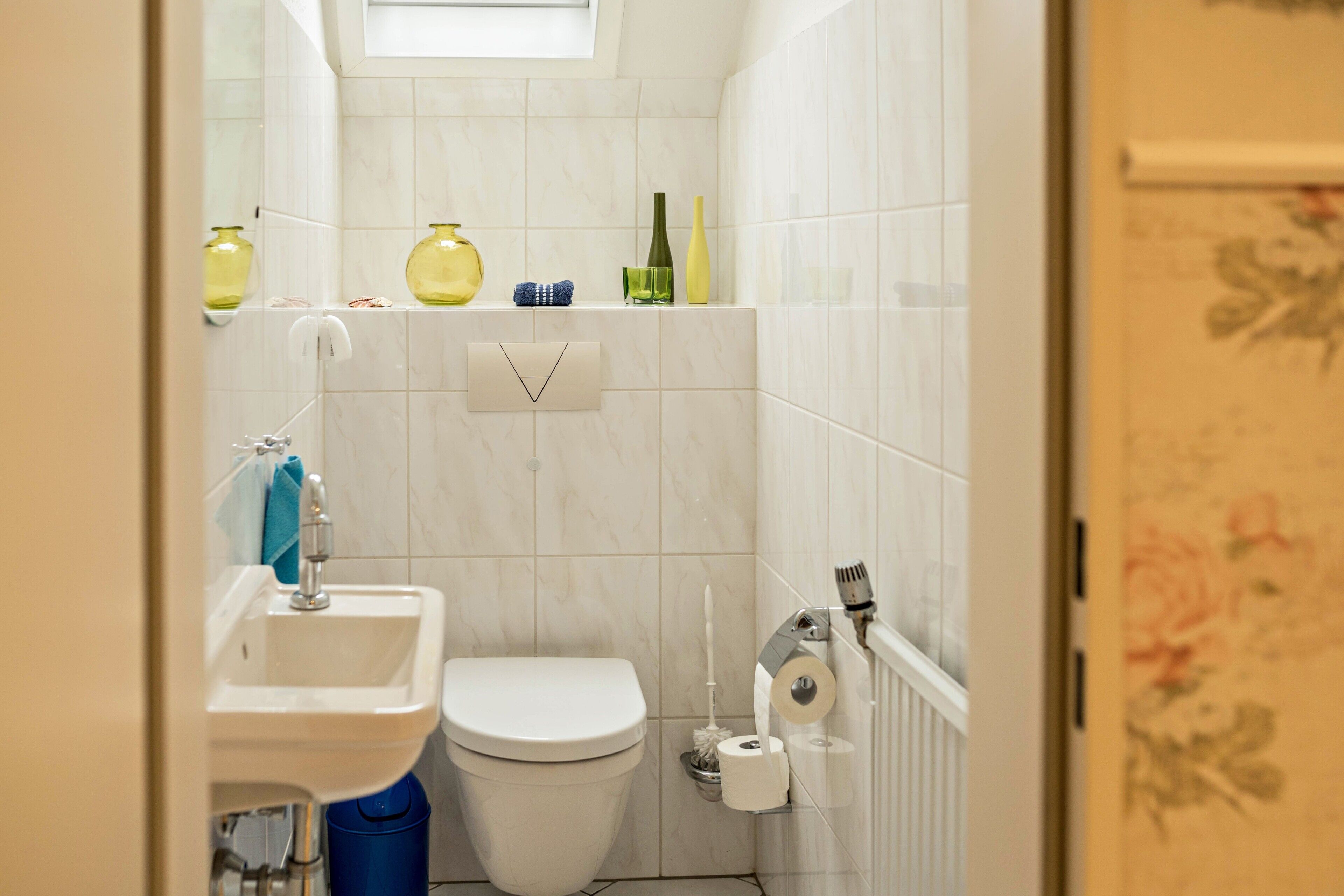 Ein kleines Badezimmer mit Toilette, Waschbecken und Ablagen für Toilettenartikel.