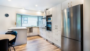 Una cocina moderna con un refrigerador de acero inoxidable, horno empotrado y microondas.