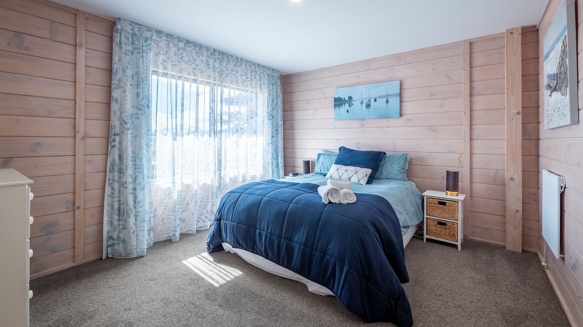 A bedroom with a bed, a nightstand, a lamp, and a painting on the wall.