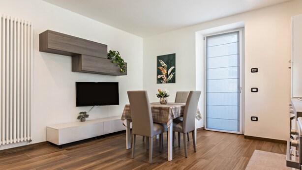 Un espace repas moderne équipé d’un téléviseur, d’une banquette et d’une table pour quatre personnes.