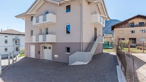 Un immeuble à plusieurs étages doté de balcons, d’un escalier et d’une cour dallée.