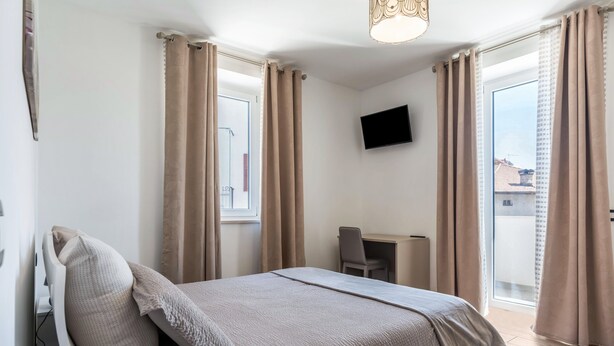 Ein Schlafzimmer mit einem Bett, einem Schreibtisch und einem Fernseher an der Wand.
