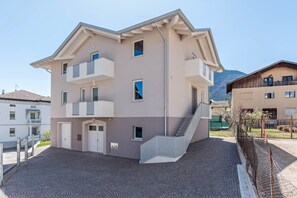 A multi-story building with balconies, a staircase, and a paved courtyard. - Apartment "Villa Vacanze Pink Lady" with Mountain View, Private Terrace & Shared Garden (Tuenno)