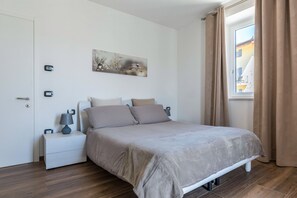 A bedroom with a bed, nightstands, a wall clock, a painting, and a window with curtains. - Apartment "Villa Vacanze Pink Lady" with Mountain View, Private Terrace & Shared Garden (Tuenno)