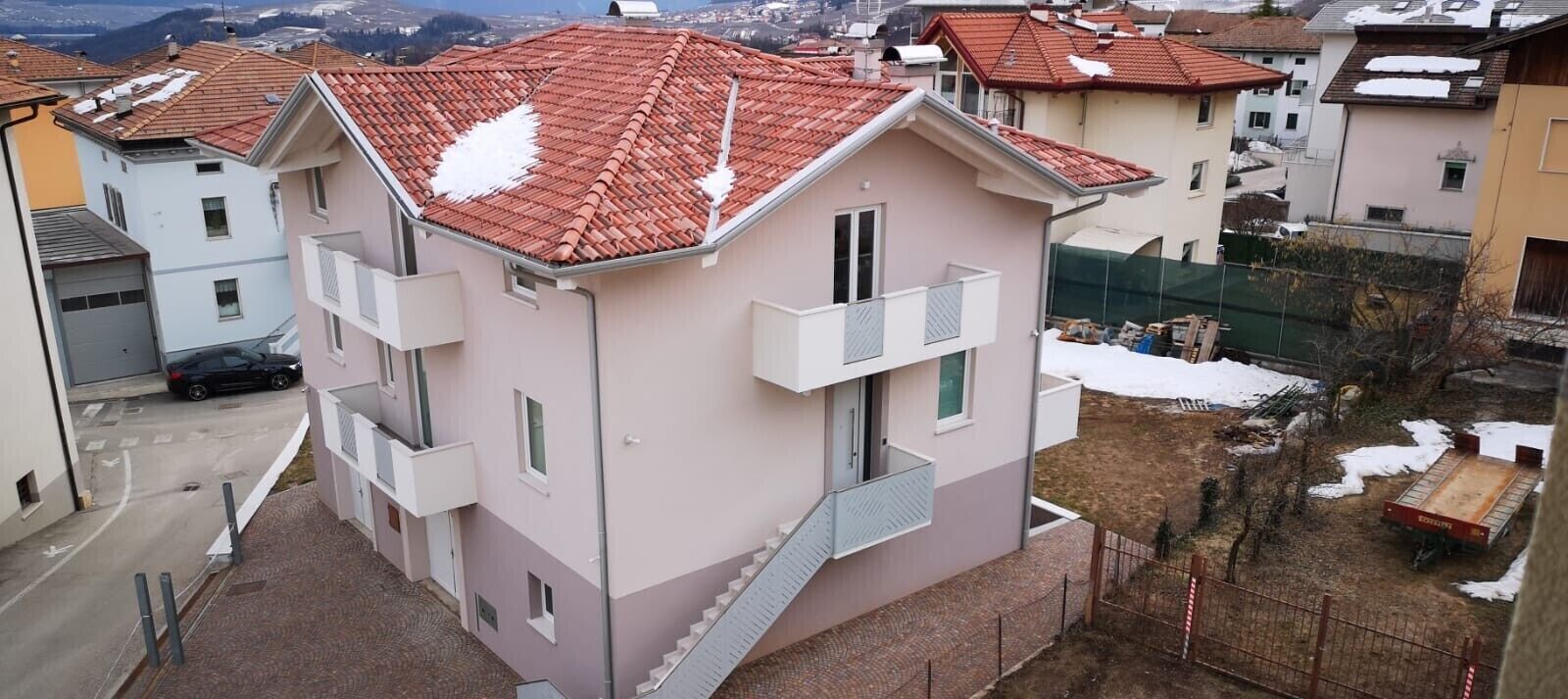 Un edificio residencial de varios pisos con techo de tejas rojas, balcones y una escalera que conduce a los pisos superiores.