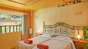 A double room with two beds, wooden floors, a window with curtains, a bedside table with a lamp, and a wall-mounted light fixture. - Finca "La Alpispa" with Pool, Fast Wi-Fi, Terrace & Garden (Valleseco)