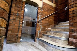 Staircase leading to a spacious interior with a glass door and brick walls.