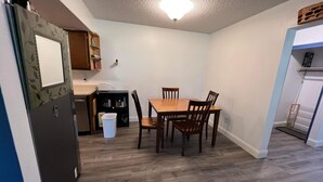 A compact kitchen with a dining area, wooden flooring, and a ceiling light fixture. - Rustic Girdwood Condo (Girdwood)