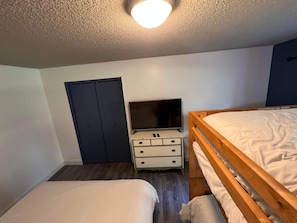 A bedroom with a bed, a dresser, a television, and a wardrobe. - Rustic Girdwood Condo (Girdwood)