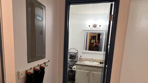A hallway leading to a bathroom with a sink, mirror, and towel rack. - Rustic Girdwood Condo (Girdwood)