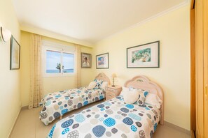 A bedroom with two beds, a window, and framed pictures on the wall.