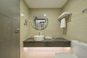 Un baño moderno con un espejo redondo, un lavamanos, un inodoro y un perchero para toallas.