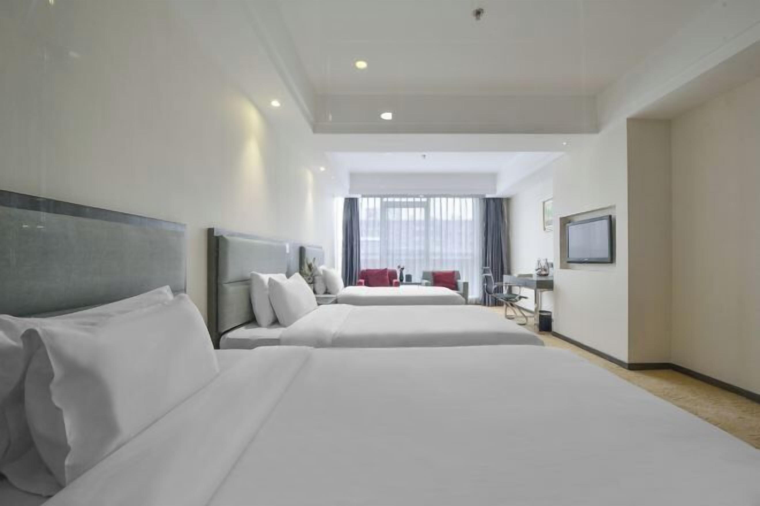 A hotel room with two beds, a desk, a chair, and a TV on the wall.