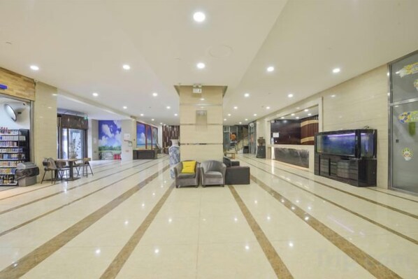 A spacious lobby with a reception desk, seating area, and a large screen.