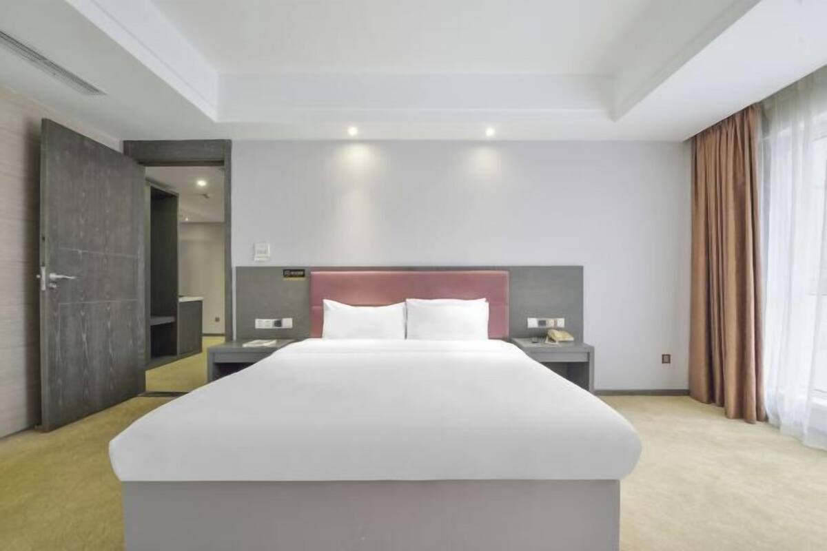 Une chambre d’hôtel moderne avec un grand lit, des tables de chevet et une vue sur la ville.