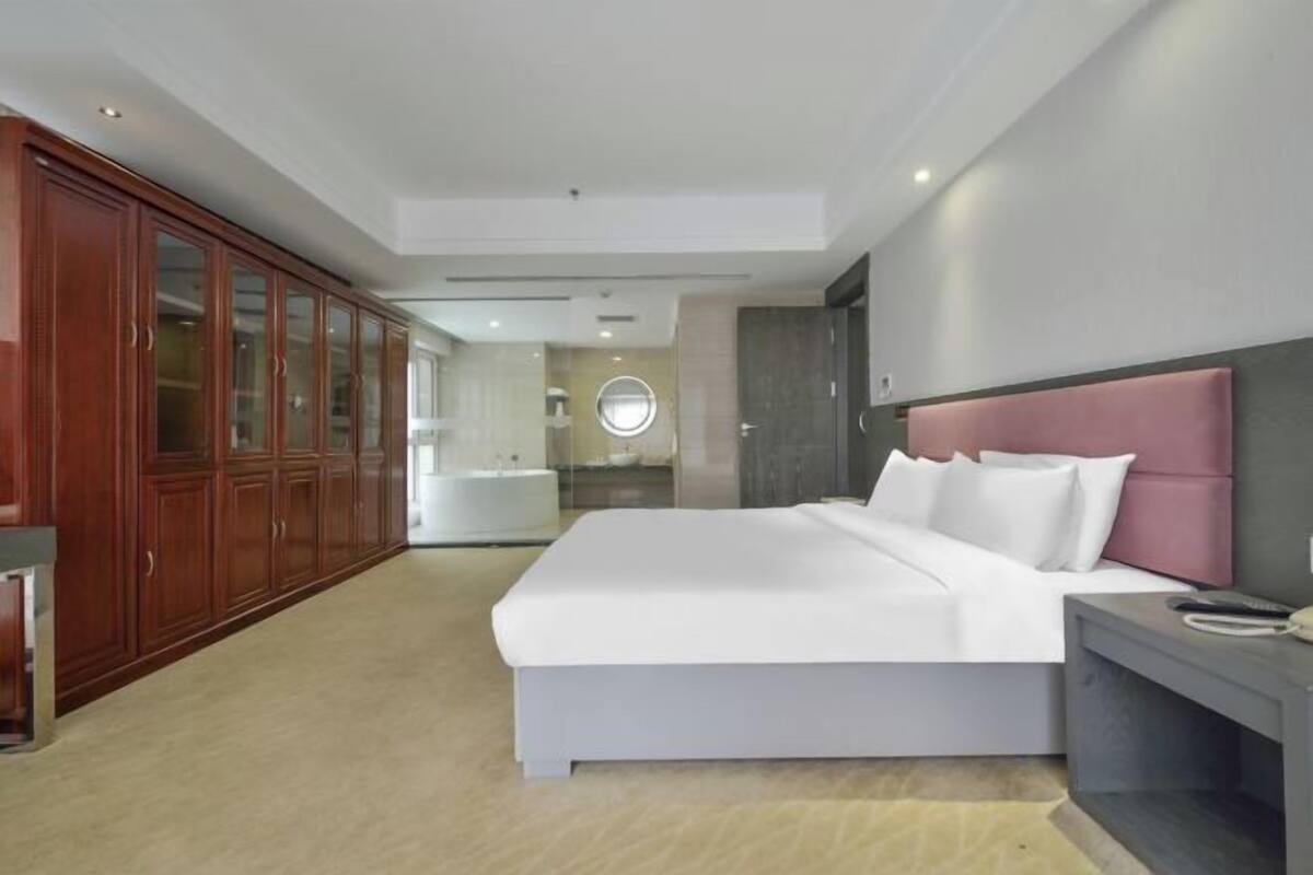 Une chambre moderne avec un grand lit, une armoire en bois et une table de chevet.