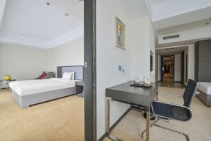 Habitación de hotel con cama, escritorio, silla y una mesita con adornos.