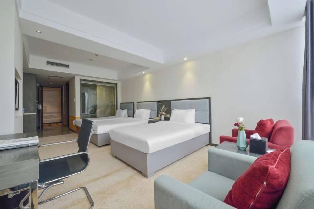 Une chambre d’hôtel avec deux lits, un bureau, une chaise et un canapé.