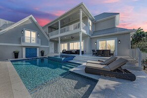 A two-story house with a swimming pool, outdoor seating, and a covered patio.