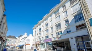 Une rue pavée bordée d’immeubles, avec un panneau indiquant « PARKING » et un restaurant appelé « Sandwicherie ».