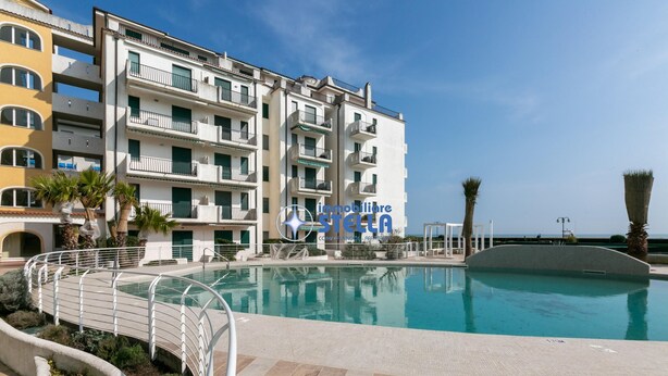 Un immeuble à plusieurs étages doté de balcons, d’une piscine et offrant une vue sur la mer.