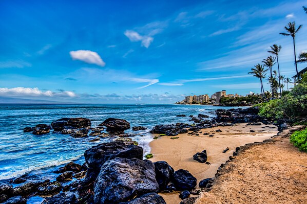 Enjoy the serene beachfront setting with a sandy shore and large rocks.