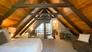 Une chambre mansardée avec un plafond en pente, un lit, un canapé et une petite table.