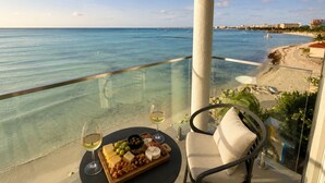 A balcony with a clear view of the sea, a table with cheese and nuts, and two glasses of wine.