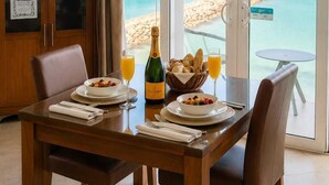 A dining area with a table set for two, a bottle of champagne, and a basket of bread.