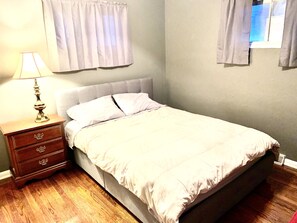 Une chambre à coucher avec un lit, une table de chevet avec une lampe et des rideaux aux fenêtres.