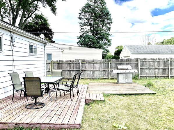A backyard with a wooden deck, a grill, and a table with chairs. - 5 bedroom 2 bath house, walk to Notre Dame, safe area (South Bend)