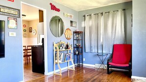 A living room with a red chair, a bookshelf, a mirror, and a 'Live Laugh Love' sign.