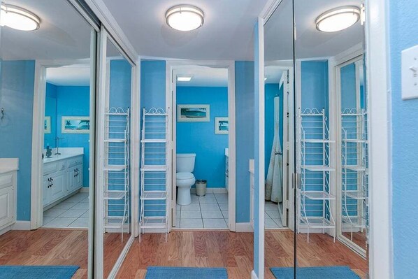 A bathroom with a blue wall, white cabinets, a toilet, and a shower area. - Oceanfront 5th floor,quiet,peaceful.beautiful views (Myrtle Beach)