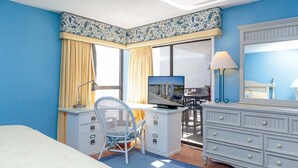 A hotel room with a bed, a desk with a computer, a chair, a dresser, and a large window with curtains. - Oceanfront 5th floor,quiet,peaceful.beautiful views (Myrtle Beach)